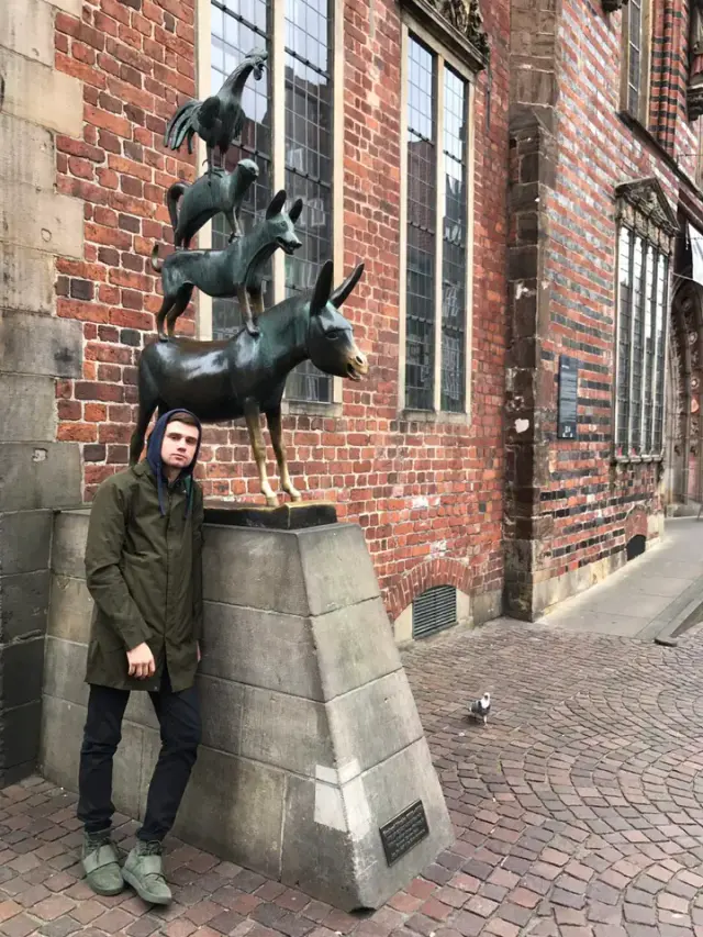 Alexey standing beside a statue in a European city