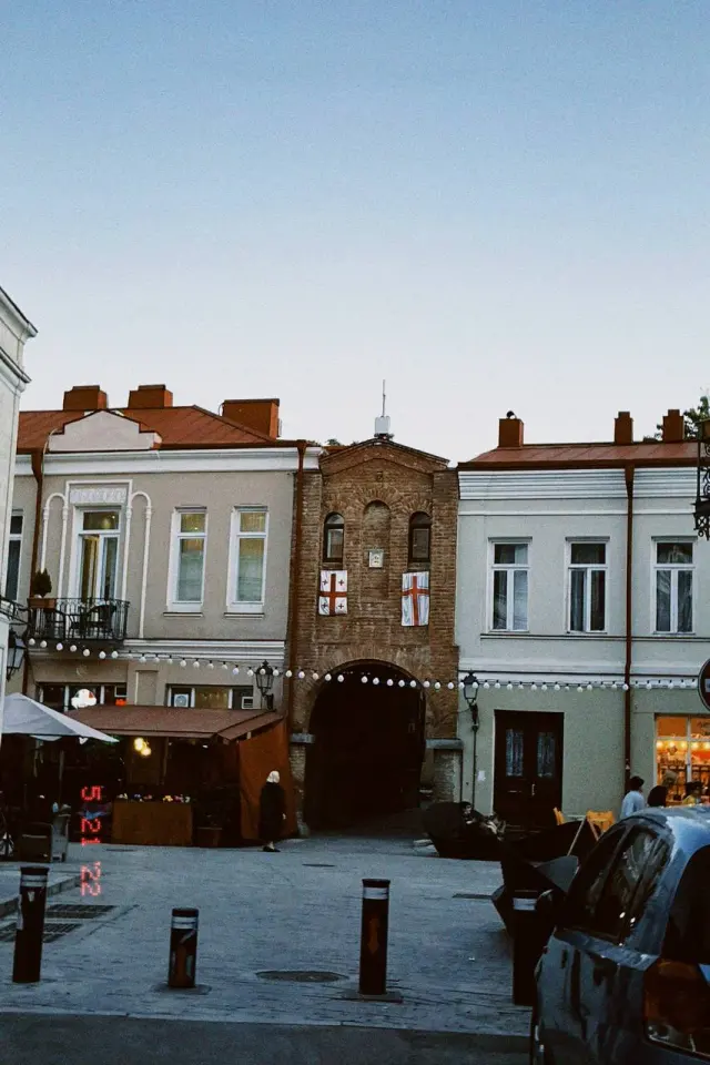 People in a sunlit square lined with old buildings