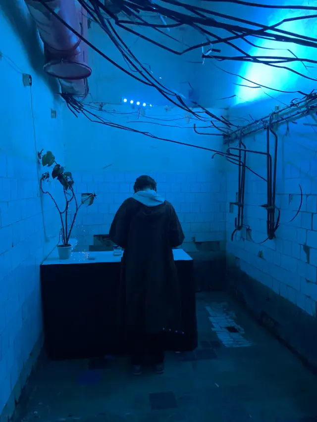 A person in front of a circular light installation in a blue-lit room