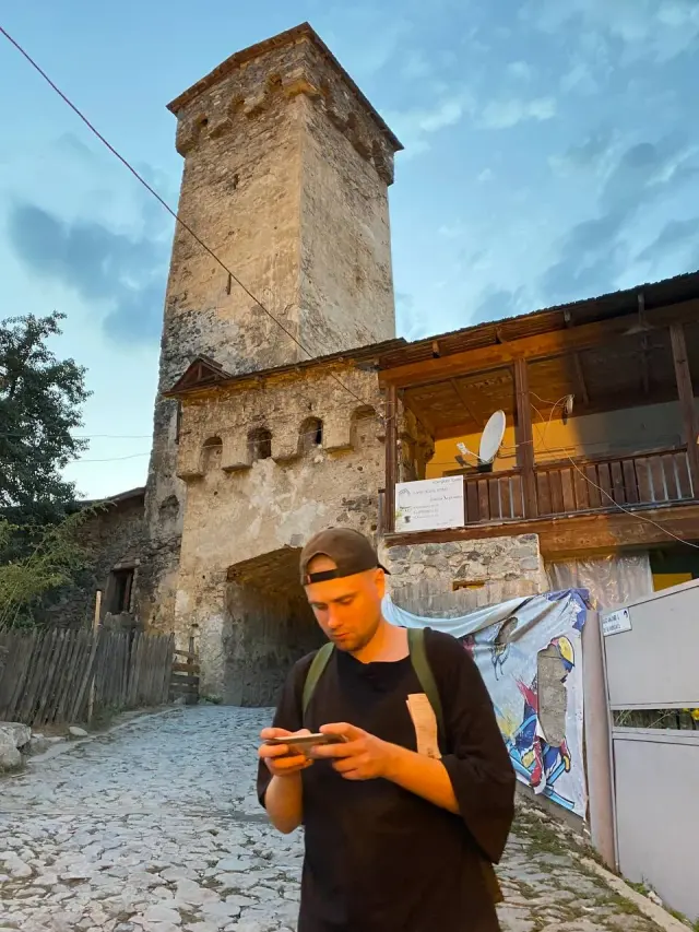 A traveller looking at a phone beside an old tower