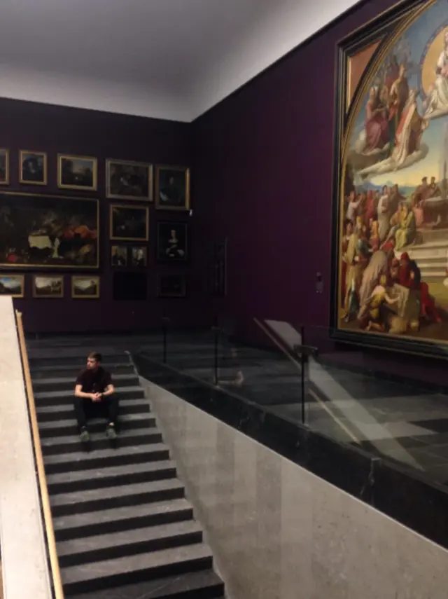 Paintings on a museum wall beside a staircase